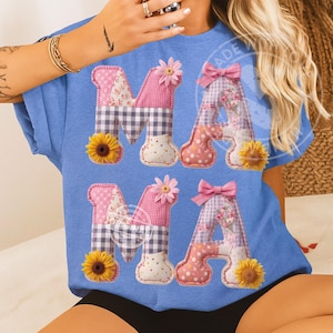 Könnte beinhalten: Hellblaues T-Shirt mit dem Wort "MAMA" in einem Patchwork-Design. Die Buchstaben sind mit rosa Blumenstoff, Vichy-Karo und Sonnenblumen verziert. Der Buchstabe "A" hat eine rosa Schleife.