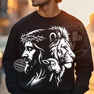 May include: Black sweatshirt featuring a white graphic of Jesus wearing a crown of thorns, a lion, and a lamb. The sweatshirt has the words "ORIGINAL" and "MADE WITH LOVE" printed on it.