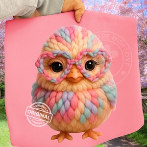 May include: A pink tote bag featuring a colorful, knitted chick wearing heart-shaped glasses. The chick has large, dark eyes and is made of pastel-colored yarn. The bag has the text "MADE WITH LOVE" and "ORIGINAL" printed on it.