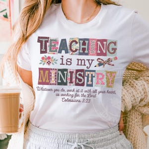 May include: White t-shirt with the words "TEACHING is my MINISTRY" in colorful block letters. The shirt also features the Bible verse Colossians 3:23. A pencil and floral design are also included.