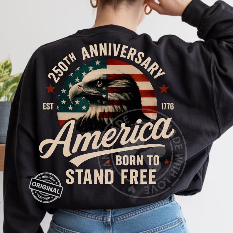May include: Black sweatshirt featuring a patriotic design. The design includes an eagle, the American flag, and the words "250th Anniversary," "America," and "Born to Stand Free." The year "1776" is also displayed. A circular "Original" logo is visible.