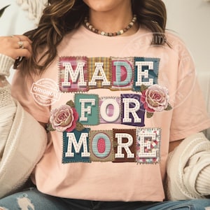 May include: A light pink t-shirt with the words "MADE FOR MORE" in a patchwork design. The letters are white with a stitched border, and the patches have various patterns. Pink roses are placed near the letters.