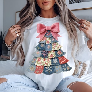 Könnte beinhalten: Weißes Sweatshirt mit einem Patchwork-Weihnachtsbaum-Design. Der Baum besteht aus verschiedenen Stoffmustern in Blau, Rot und floralen Drucken, gekrönt von einer rosa Schleife. Schneeflocken- und Blumendetails sind sichtbar.