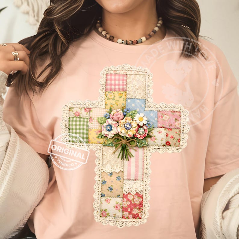 May include: A light pink t-shirt featuring a patchwork cross design. The cross is adorned with floral patterns, lace trim, and a bouquet of flowers. The word "ORIGINAL" is printed on a white label.