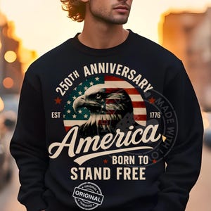 May include: Black sweatshirt with a graphic featuring an eagle, the American flag, and the text "250th Anniversary America Born to Stand Free." The design includes the year 1776 and the word "Original."