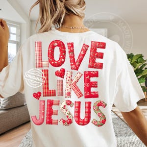Op de afbeelding: Wit T-shirt met de woorden "LOVE LIKE JESUS" in rode letters in patchwork-stijl. De letters hebben bloemen-, ruit- en effen patronen. Het shirt heeft een relaxte pasvorm en een ronde hals.