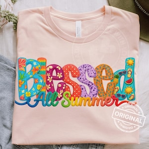 Puede incluir: Camiseta rosa claro con la frase bordada "Blessed All Summer" en letras coloridas y estampadas. El diseño incluye iconos de verano como gafas de sol, una rodaja de sandía y una piña.