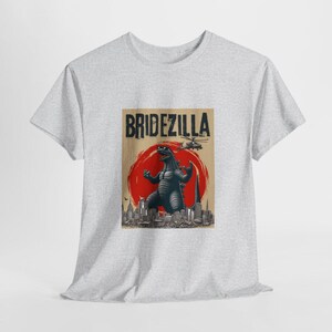May include: A gray t-shirt with a graphic print of a Godzilla-like monster in front of a cityscape. The text "Bridezilla" is printed above the monster.