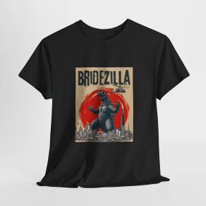 May include: Black t-shirt with a graphic print of a Godzilla-like monster in front of a city skyline. The text "Bridezilla" is printed above the monster.