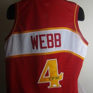 May include: A red basketball jersey with white and gold trim. The back of the jersey has the name "WEBB" and the number "4" in gold. The number is signed in black.