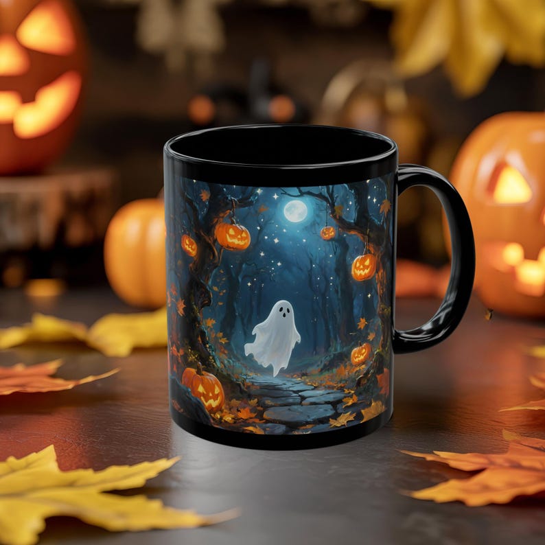 May include: Black ceramic Halloween mug featuring a spooky forest scene with a ghost, jack-o'-lanterns, and a full moon. The mug has a black handle and interior, perfect for seasonal beverages.