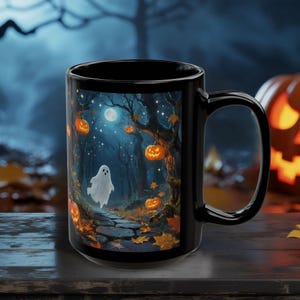 May include: Black ceramic mug featuring a Halloween-themed design. The artwork depicts a spooky forest scene with a ghost, pumpkins, and a full moon. The mug has a large handle and a glossy finish, perfect for seasonal beverages.