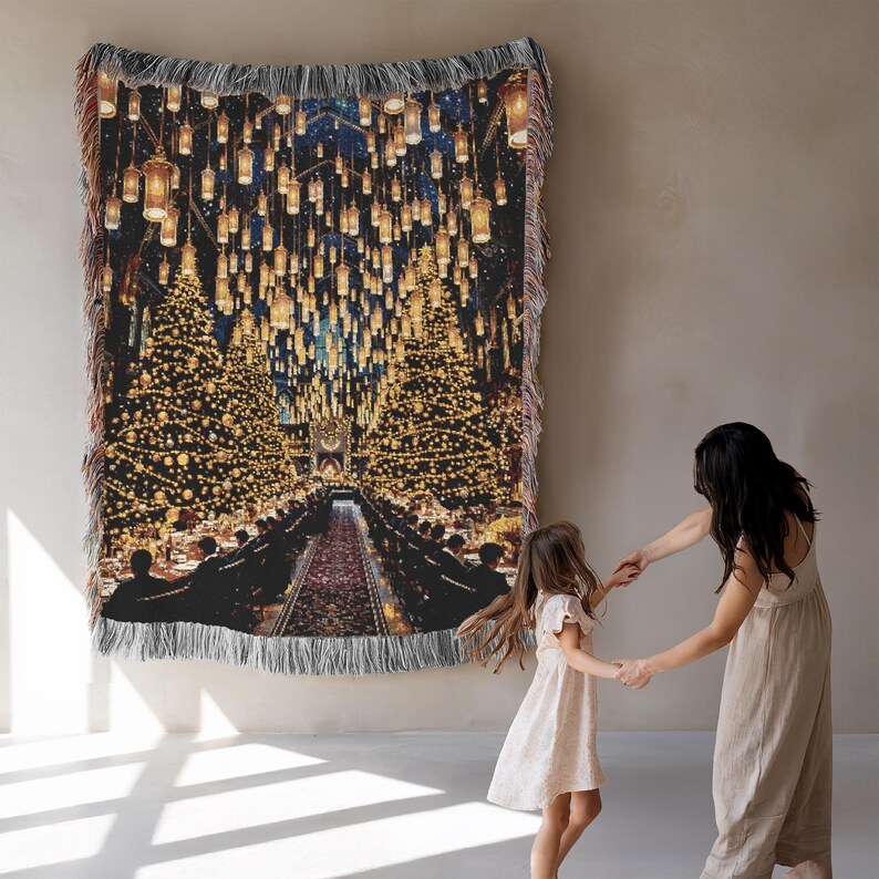 May include: Woven tapestry blanket depicting a grand hall with floating candles and festive lighting. The blanket has a black background with gold and white accents, and a fringed edge. The blanket is hanging on a wall.