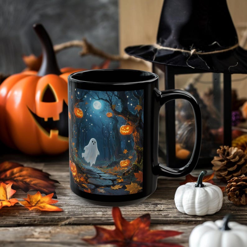 May include: Black ceramic mug featuring a Halloween-themed illustration. The design depicts a spooky forest scene with a ghost, pumpkins, and a full moon. The mug is surrounded by fall foliage and decorative pumpkins.