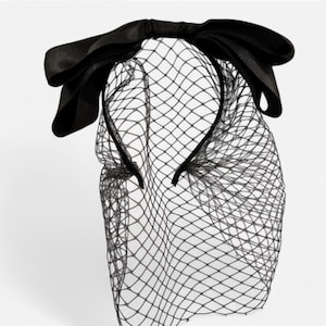 May include: A black headband with a large black bow and a black tulle veil.