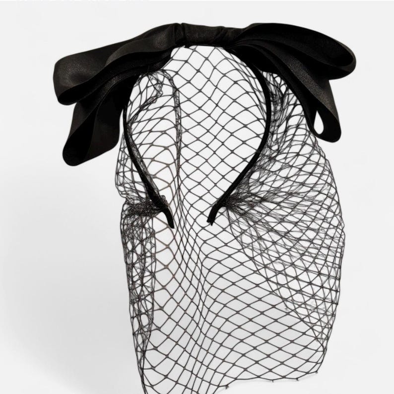 May include: A black headband with a large black bow and a black tulle veil.