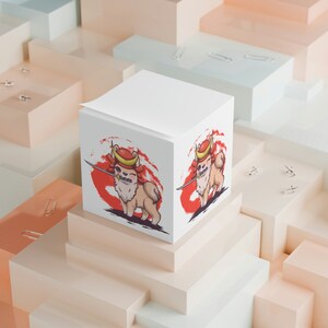 May include: A white cube notepad with a red and white illustration of a cartoon dog wearing a samurai helmet and holding a sword. The dog is on a red and white background.