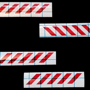 May include: Four red and white striped warning tape decals on a white background with a grid pattern.