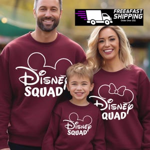 Puede incluir: Una familia de tres personas con sudaderas color granate con orejas de Mickey Mouse blancas y el texto "Disney Squad". Las sudaderas de los adultos tienen las orejas de Mickey Mouse completas, mientras que la sudadera del ni&ntilde;o solo tiene la parte superior de las orejas.