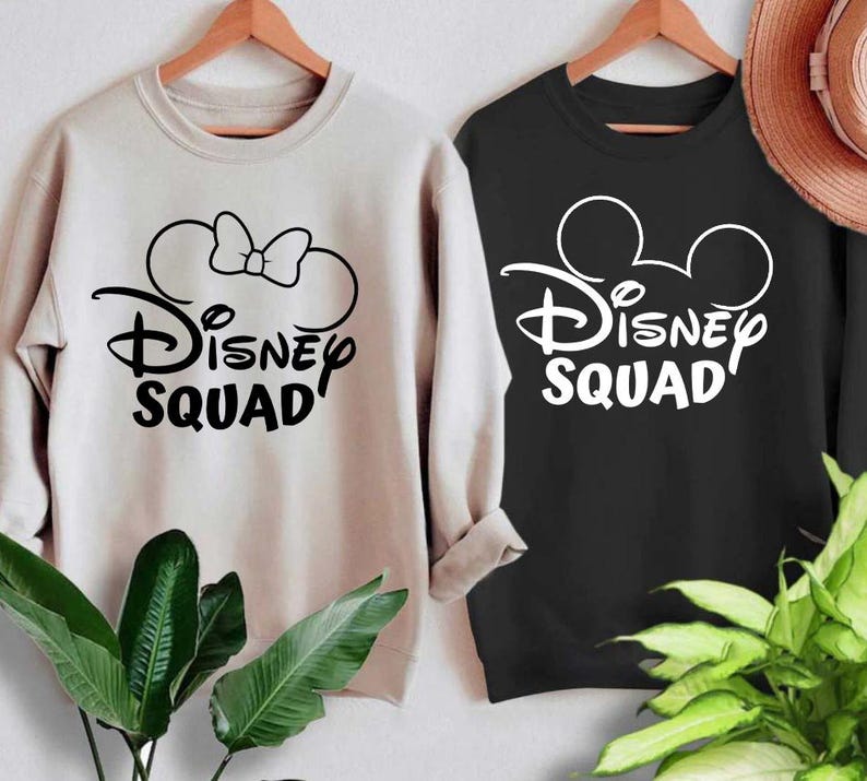 Puede incluir: Dos sudaderas con un gr&aacute;fico de Disney Squad. Una sudadera es beige con un gr&aacute;fico negro de orejas de Minnie Mouse y un lazo. La otra sudadera es negra con un gr&aacute;fico blanco de orejas de Mickey Mouse.