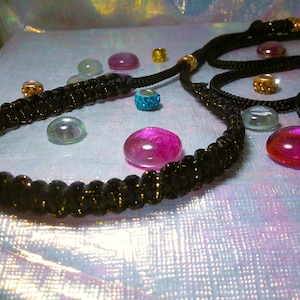 May include: A black braided cord necklace with gold beads and a variety of colorful glass beads.