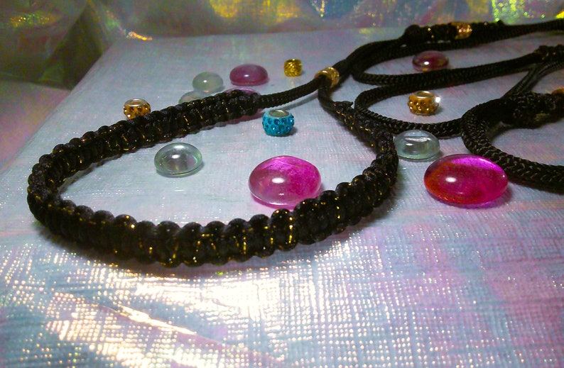 May include: A black braided cord necklace with gold beads and a variety of colorful glass beads.