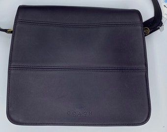 May include: A black leather shoulder bag with a gold buckle and the text "COACH NEW YORK" on the front.