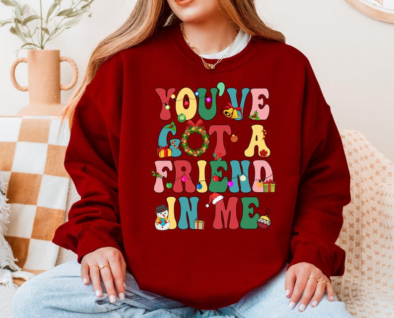 A woman wearing a red sweater with the text "YOU'VE GOT A FRIEND IN ME" printed on it.