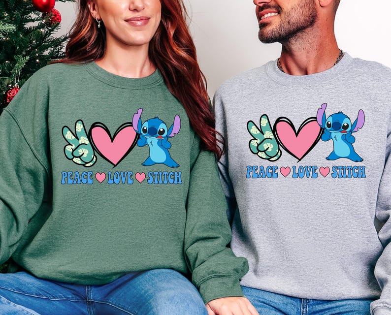 A woman and a man are sitting next to each other, both wearing sweatshirts with a peace symbol and a character from the Lilo & Stitch movie franchise.