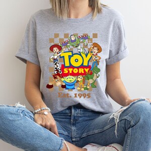 a woman sitting on the floor wearing a toy story t - shirt