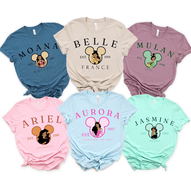 Puede incluir: Seis camisetas diferentes con princesas de Disney con sus nombres y el a&ntilde;o en que se establecieron. Las camisetas son de varios colores, incluyendo azul, rosa, beige, azul claro y verde.