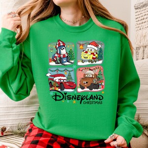 A woman wearing a green sweater with a Disney Cars Christmas-themed design.
