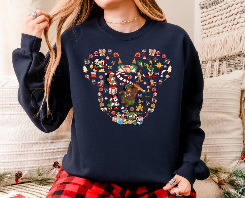 A woman wearing a navy blue sweatshirt with a colorful, pixelated design of various Christmas-themed characters and symbols.