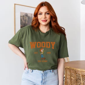 a woman with red hair wearing a woody t - shirt