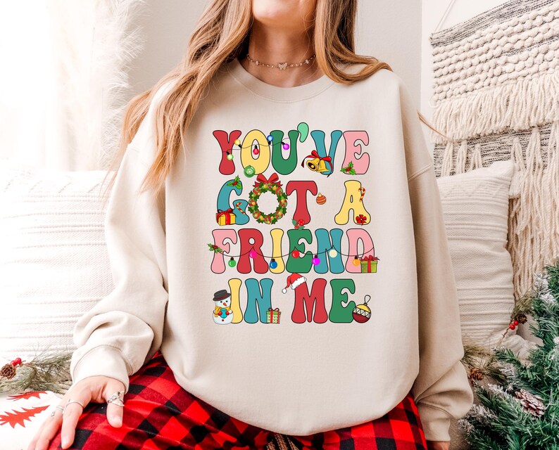 A woman wearing a white sweatshirt with a colorful text design that says "You've Got a Friend in Me".