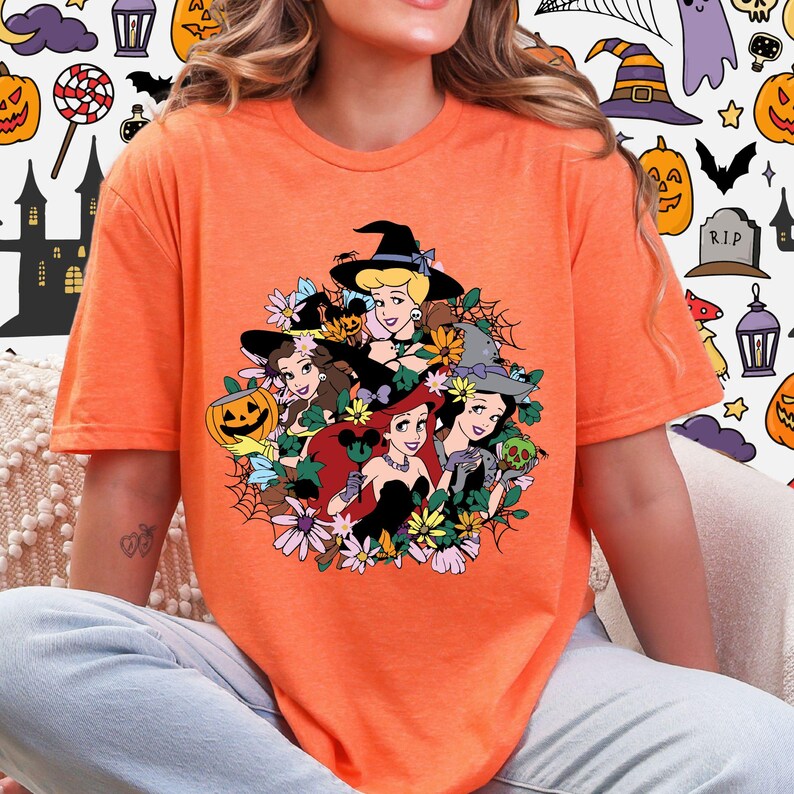 A woman wearing an orange t-shirt with a graphic design featuring cartoon characters and Halloween-themed elements.