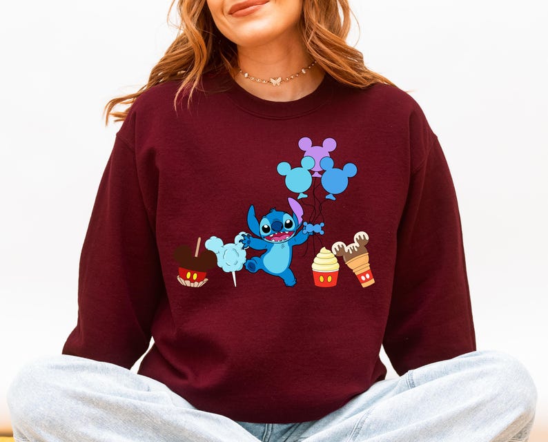 A woman wearing a burgundy sweater with a cartoon character and various Disney-themed items printed on it.