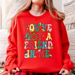 A person wearing a red sweater with the text "YOU'VE GOT A FRIEND IN ME" printed on it.
