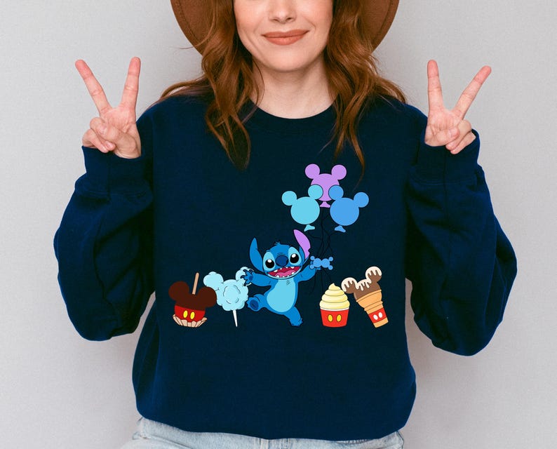 A woman wearing a blue sweatshirt with a cartoon character and various Disney-themed items printed on it.