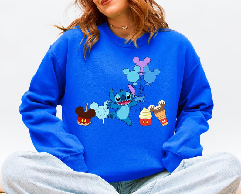 A woman wearing a blue sweatshirt with a cartoon character and various Disney-themed items printed on it.