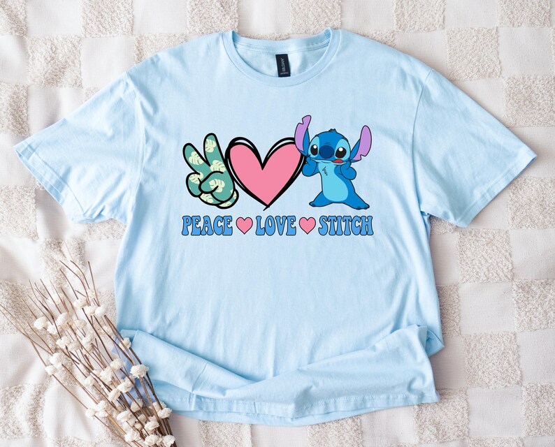 A light blue t-shirt with a peace sign and a heart graphic, along with the text "Peace Love Stitch" printed on it.