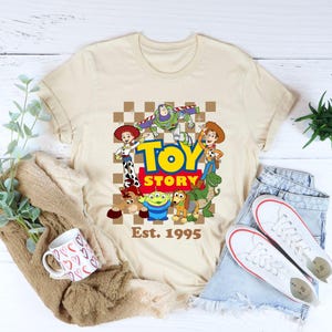 a toy story t - shirt sitting on top of a pile of clothes