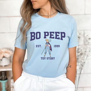 a woman wearing a blue t - shirt that says bo peep est 1989 toy