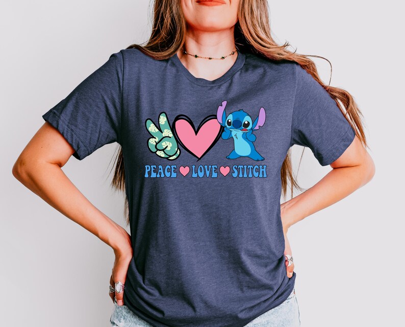 A woman wearing a gray t-shirt with a graphic design featuring a character from the Lilo & Stitch movie franchise and the text "Peace Love Stitch".