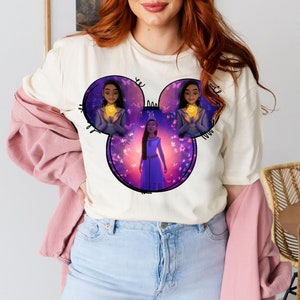 May include: A white t-shirt with a purple and blue graphic of a Disney character with butterflies. The graphic is in the shape of Mickey Mouse ears.