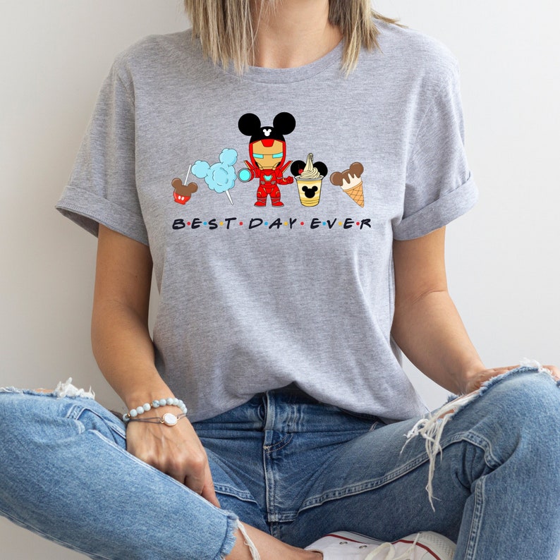 May include: Gray t-shirt with a cartoon image of Iron Man wearing Mickey Mouse ears and holding a Mickey Mouse ice cream cone. The text "BEST DAY EVER" is printed below the image.