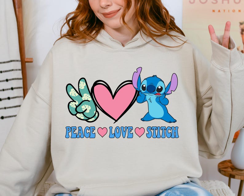 A woman wearing a white hoodie with a graphic design featuring a character from the Lilo & Stitch movie franchise, along with the text "PEACE LOVE STITCH".