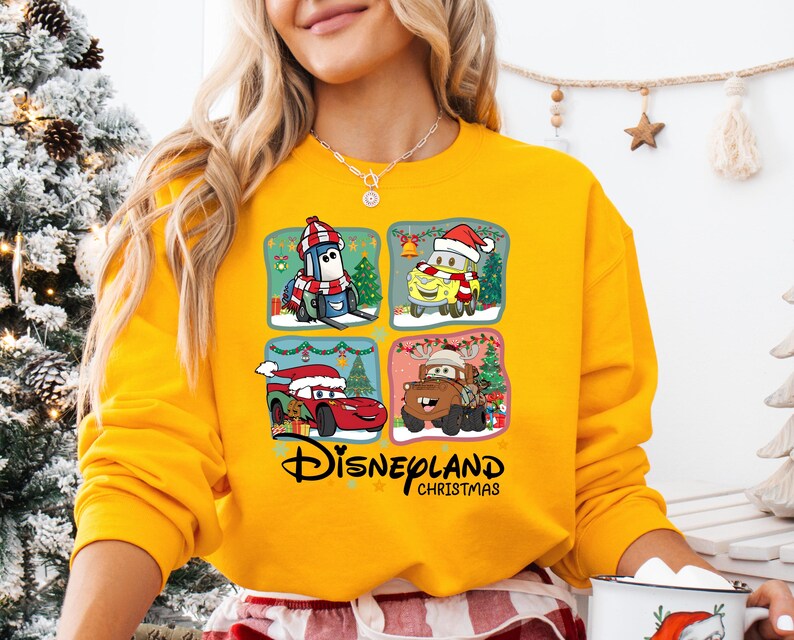 A woman wearing a yellow sweater with a Disney-themed graphic on it, including characters from the Disney movie Cars.