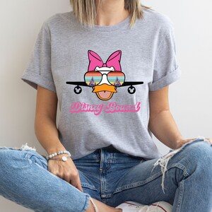 a woman sitting on the floor wearing a t - shirt with a cartoon character on