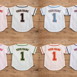 Op de afbeelding: Acht honkbalshirts met krijtstrepen in verschillende kleuren. Elk shirt heeft "YOUR NAME" boven het nummer 1. Kleuren zijn onder meer rood, zwart, blauw en groen. De shirts worden op een houten oppervlak weergegeven.